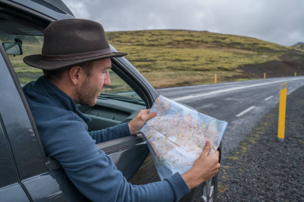 istock Young man in car looking at map, road trip concept vacations 994838546