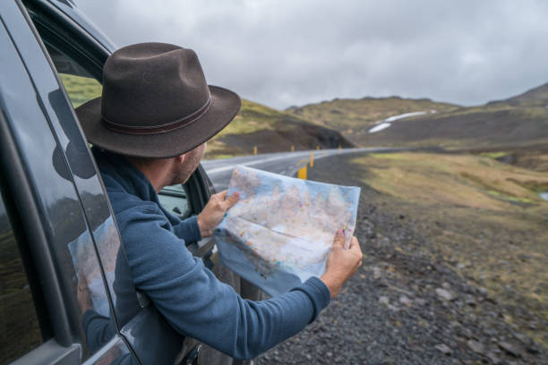 istock Young man in car looking at map, road trip concept vacations 994838566