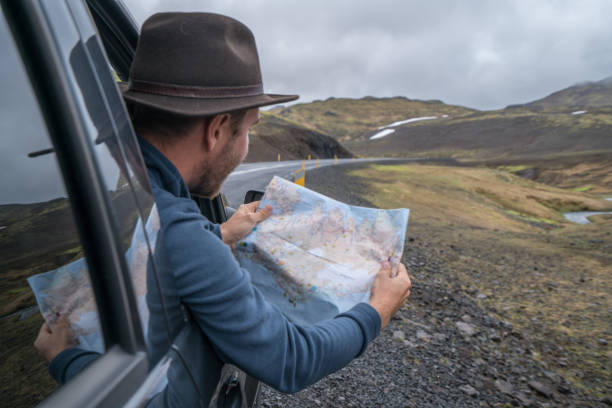 istock Young man in car looking at map, road trip concept vacations 994838572