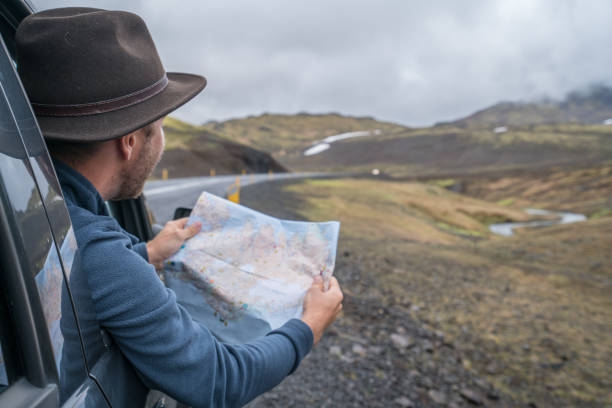 istock Young man in car looking at map, road trip concept vacations 994838580