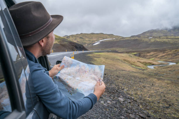 istock Young man in car looking at map, road trip concept vacations 994839348