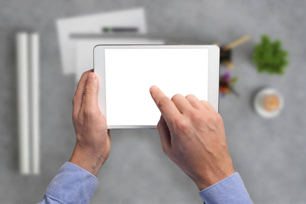 istock Man holding tablet knolling overhead view 994842286