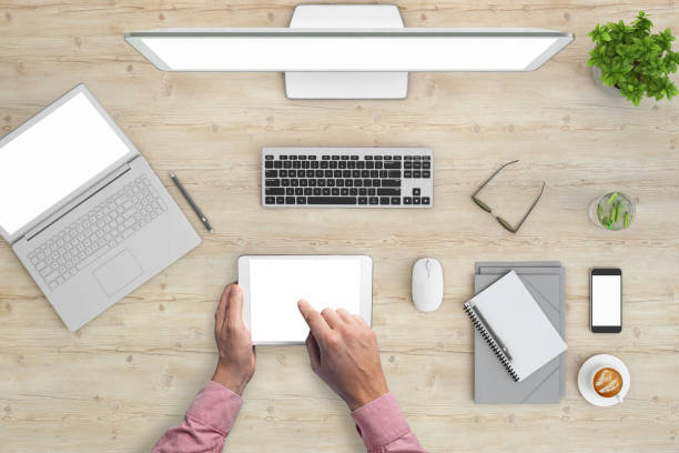 Man using digital tablet with blank screen.  Office knolling overhead concept,  blank papers with markers, and a plant.  blank screen template designer business background template