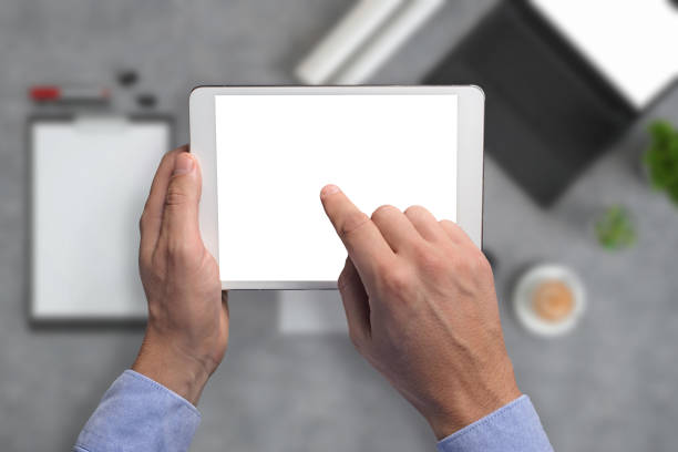 istock Man holding tablet knolling overhead view 994842414