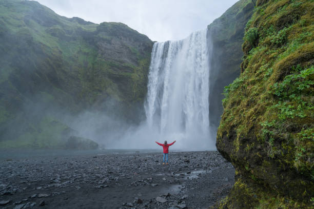 istock Young man arms outstretched at spectacular waterfall in Iceland 994848776