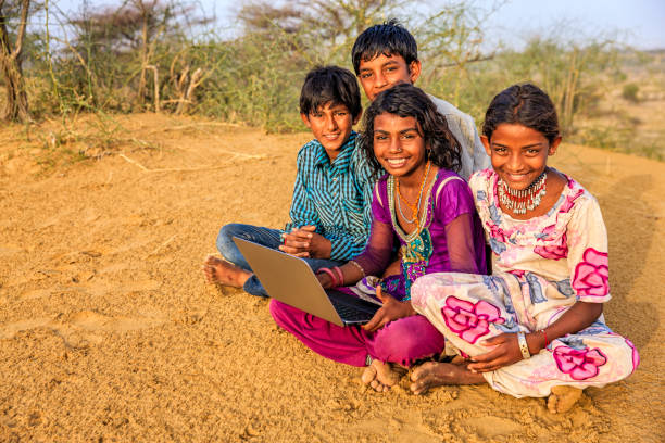 istock Happy Indian children using laptop, desert village, India 994860744