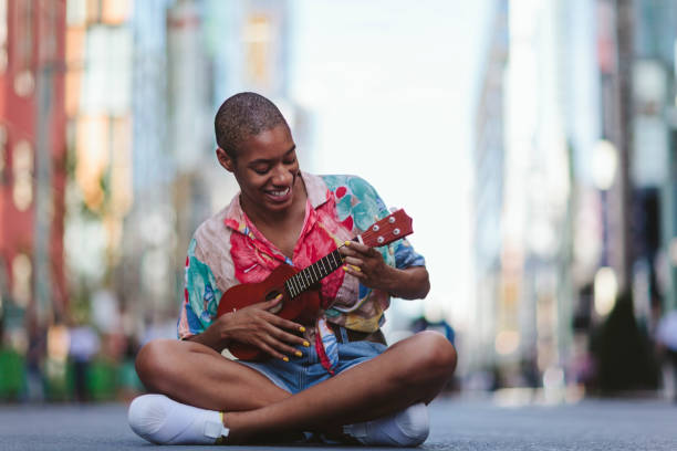 istock Young woman playing ukulele in street 994866324