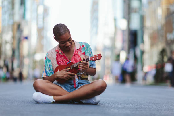 istock Young woman playing ukulele in street 994866432