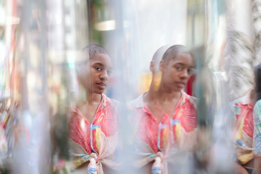 A portrait of an African American young woman reflected on a multiple mirrors.