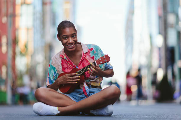 istock Young woman playing ukulele in street 994866542
