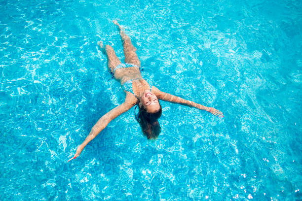istock Beautiful young woman swimming in a pool while smiling 994872574