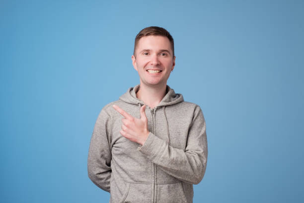 istock Cheerful handsome man showing direction and pointing with finger 994890924