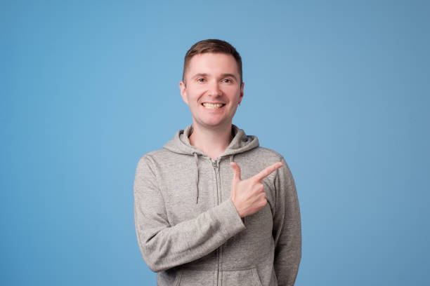 istock Cheerful handsome man showing direction and pointing with finger 994890956