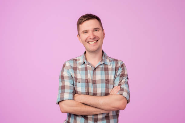 istock Confident young handsome man keeping arms crossed and smiling while standing against blue white background 994898338