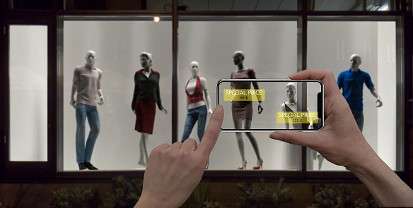 Augmented reality marketing concept. Hand holding digital tablet smart phone use AR application to check special sale price in retail fashion shop, mall interior design