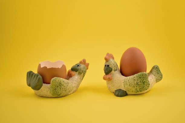 Easter egg on a yellow background. Spring decoration images. Ceramic egg cup on a yellow background. Breakfast still life. Two chickens with eggs