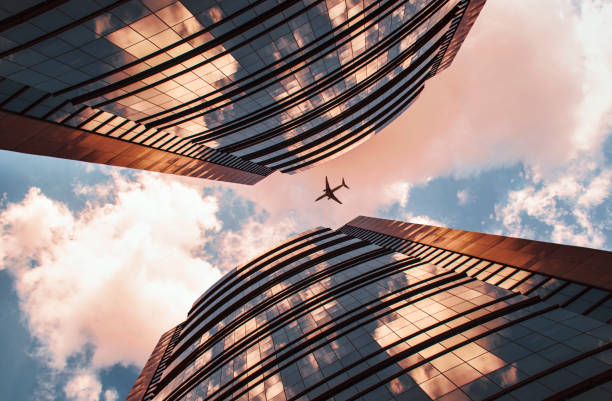 istock Low angle view of twin buildings and plane 995011010