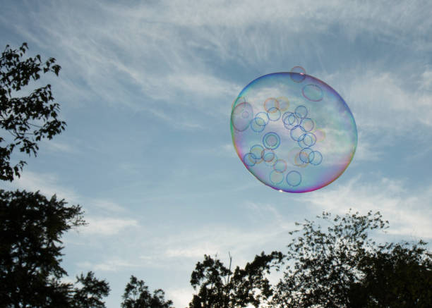 istock Big soap bubble with small soap bubbles inside flying in the sky 995022296