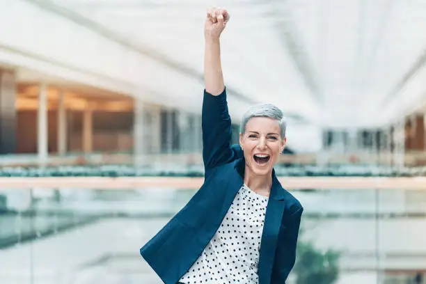 Excited businesswoman with arm raised in triumph
