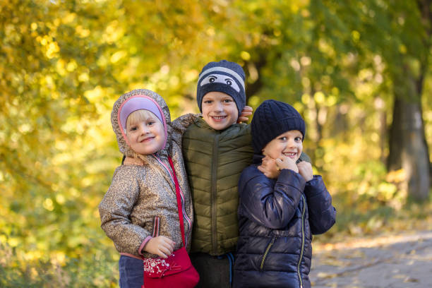 group of happy three kids having fun outdoors in autumn park. cute children enjoy hugging together against golden fall background. best frend forever and happy childhood concept - frend imagens e fotografias de stock