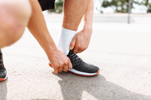 istock Athlete tying his shoelaces squatting, close-up, morning training with a young man, rest before training 995043512