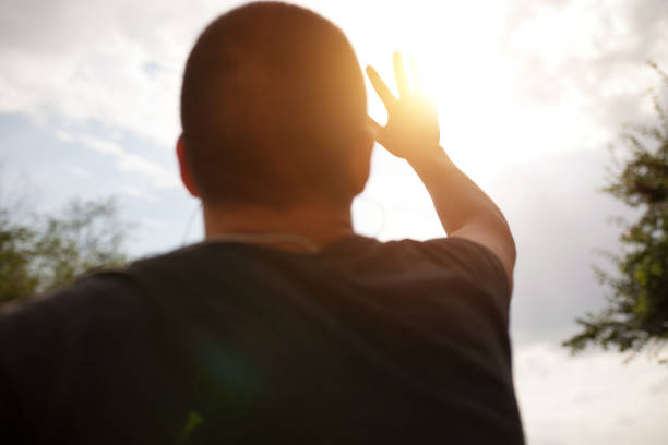 istock a hand reaches for the sky and covers the sun, the sun's rays make their way through the hand, close - up, bright sunlight 995043698