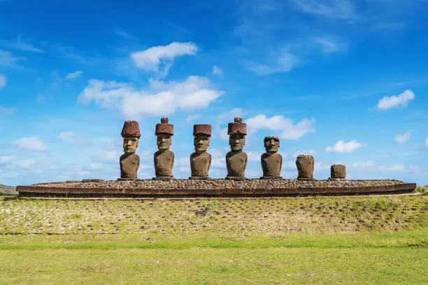 Ahu Nau Nau, Seven Moais side by side in a row wearing ancient headgear at Anakena Beach under sunny summer sky looking towards the beach and pacific ocean. Ahu Nau Nau - Anakena - is also known as Haŋa rau o te 'ariki - The bay of the king beach. Anakena Rapa Nui National Park, Hanga Roa, Easter Island, Isla de Pascua, Polynesia, Oceania, Chile