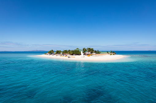 Beautiful small island in the middle of the south pacific ocean with beach huts, palm trees, surrounded with beautiful clear turquoise water. Small Islet, Mamanuca Islands, Fiji, Melanesia, Oceania