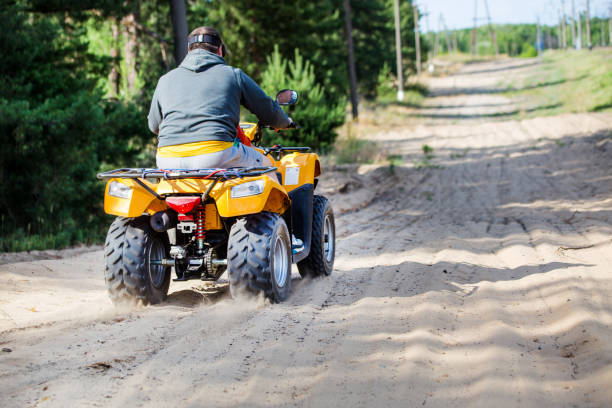 istock A man riding ATV on a sand road, back view 995071836