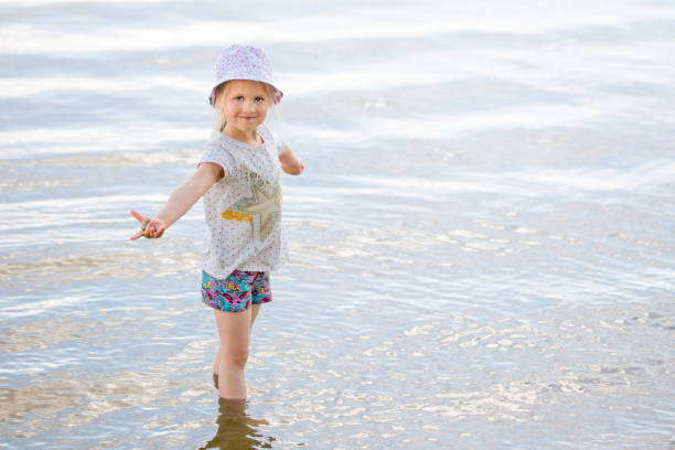 istock Little blond girl playing with water on a lake shore 995071932