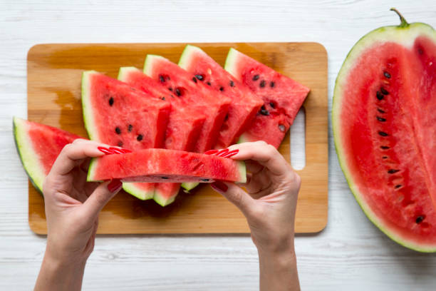 istock Women's hands hold a piece of watermelon, top view. 995076468