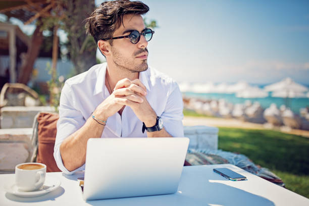 istock Young businessman is working and drinking coffee on the beach 995088146