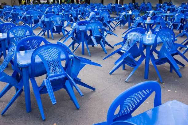 Photo of empty blue plastic chairs and tables outside, preparing for the holiday, no people