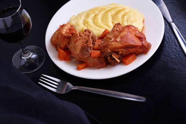 istock Chicken meat under souce with carrots and onions and smashed potatoes on black table 995102640