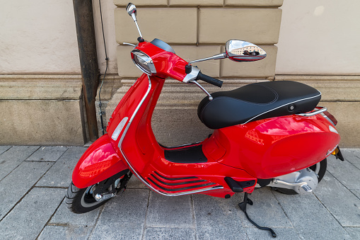 Munich, Germany - june 09, 2018: Iconic red Vespa,old fashioned Italian motorcycle, is parked on the street sidewalk in Munich center.