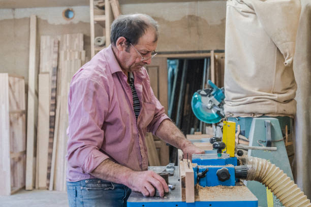 der senior 60 jahre alten mann, tischler und sashman, handwerker, arbeiten mit der industriellen fräsmaschine bei der kleinen holz-fabrik - 60 65 years stock-fotos und bilder