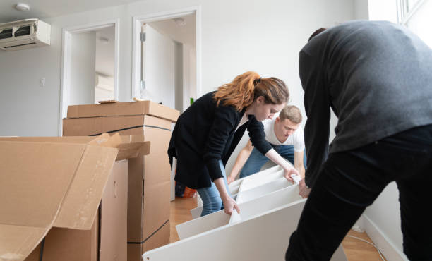 the family moving in to the new apartment. the young 30 years old man and two teenage girls, sisters, unboxing and assembling furniture. - independence lifestyles smiling years imagens e fotografias de stock