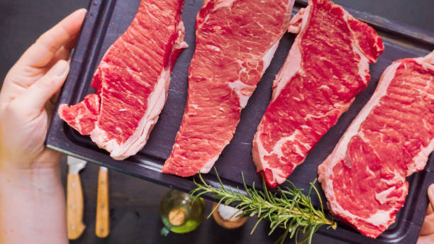 istock Raw New York strip steaks on a wood cutting board. 995117106