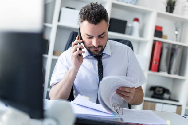 istock A man is sitting in the office, working with documents and talking on the phone. 995117132