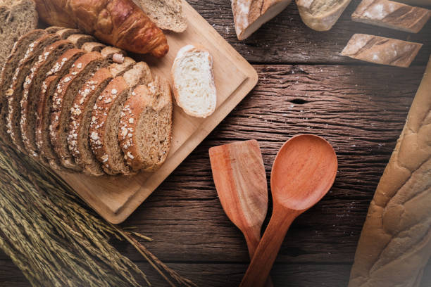 istock Fresh baked bread on dark wood table with copy space background  still life composition with wheat flour spread around with rice wheat. 995117258