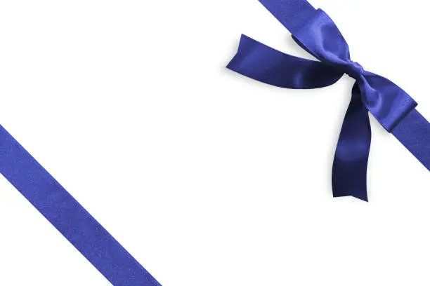 Photo of Blue bow satin navy blue ribbon band stripe fabric on corner (isolated on white background with clipping path) for Christmas holiday gift box present wrap design decoration ornament element