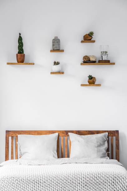 枕と毛布明るい寝室のインテリアでベッドの木製のヘッドボード上の棚に小さな装飾と白い壁のクローズ アップ。本物の写真。 - pillow headboard wall bedroom ストックフォトと画像