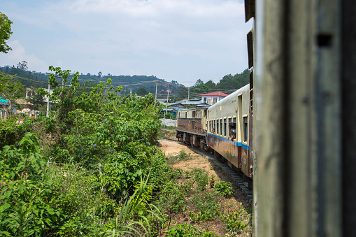 A Myanmar Railways train travels through a rural area near Kalaw.