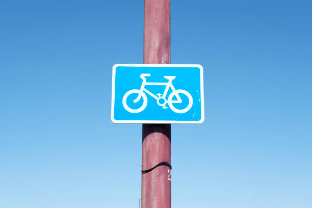 istock Cyclists riding road highway lane warning sign post blue sky background information 995220462