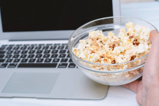 istock Popcorn in bowl and laptop playing movie 995228454