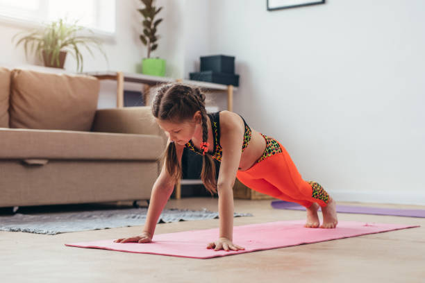 istock Little girl doing plank exercise at home. 995242106