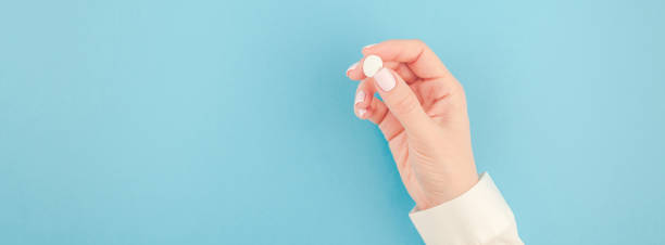 istock Female hand holding a white pill 995286580
