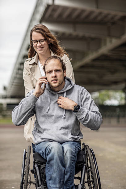 istock Wheelchair using young man and his girlfriend travelling around a modern city 995291588