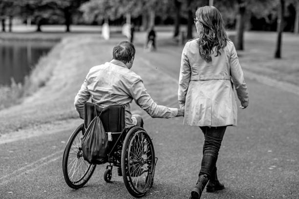 old handicapped man sitting on wheelchair in the park and looking somewhere, sepia tone