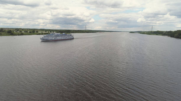 Aerial view large white cruise ship on river Volga in countryside. Cruise ship on the river through the green trees.